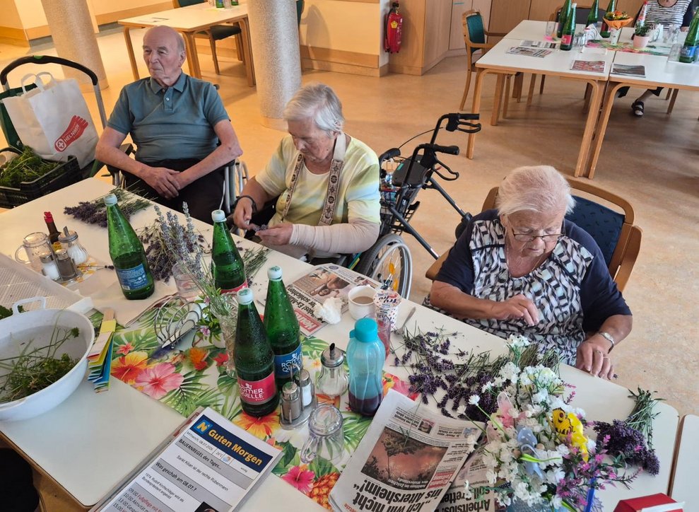 Bewohnerinnen rebeln Lavendel ab. Bewohner im Rollstuhl sitzt daneben.