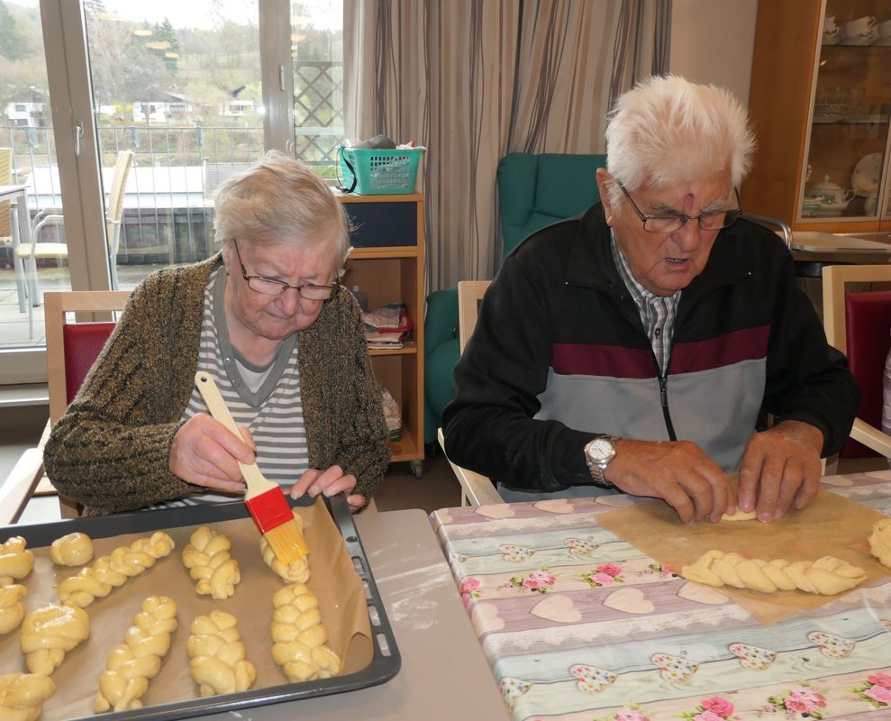Eine Dame und ein Herr backen Osterkränze.